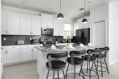 a kitchen with white cabinets and a island with bar stools at Chic & Spacious Best Vacation Home in Kissimmee