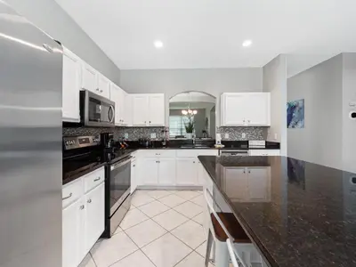 a kitchen with white cabinets and black counter tops at bsv_villa2633 in Kissimmee