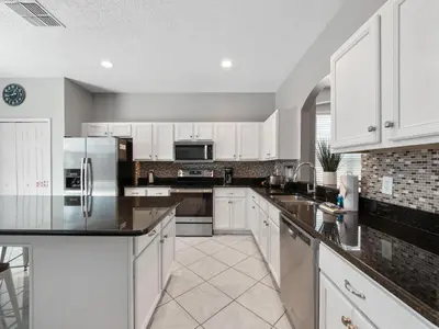 a kitchen with white cabinets and black counter tops at bsv_villa2633 in Kissimmee