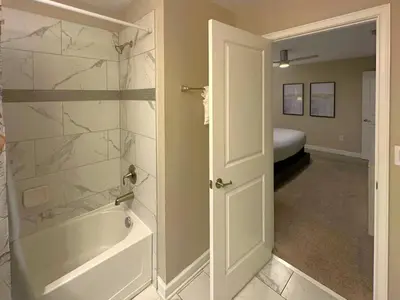 a bathroom with a tub and a bedroom with a bed at Charming 4BR with Private Heated Pool & BBQ Grill in Kissimmee
