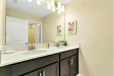 a bathroom with two sinks and a large mirror at Charming 4BR with Private Heated Pool & BBQ Grill in Kissimmee