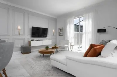 a white living room with a white couch and a tv at Chic Retreat - Unforgettable Stay in Kissimmee