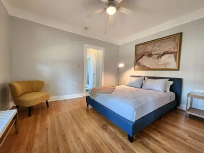 a bedroom with a bed and a chair and a ceiling fan at Cozy Vintage Bungalow @Mills50 District in Orlando