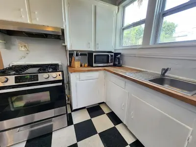 a kitchen with white cabinets and a stove and a sink at Cozy Vintage Bungalow @Mills50 District in Orlando