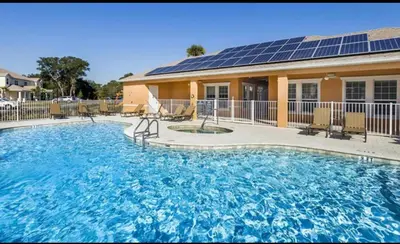 a large swimming pool with solar panels on a house at Magical Serenity in Orlando