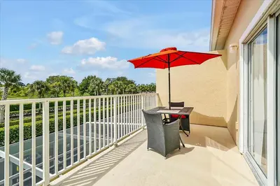 a balcony with a table and a red umbrella at Magical Serenity in Orlando