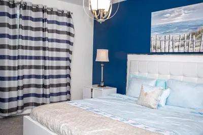 a bedroom with a bed with blue walls and a chandelier at Home 6BR - Prime Location in Kissimmee