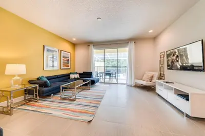 a living room with a blue couch and a tv at Ultimate Getaway - Your Best Vacation Home in Orlando