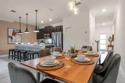 a dining room and kitchen with a wooden table and chairs at Stunning Themed Home Private Pool Ideal Location in Kissimmee