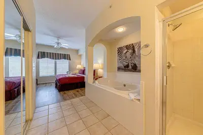 a bathroom with a bath tub and a bedroom at Exquisite 3 Bdr Condo Minutes to Disney in Orlando