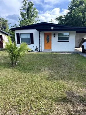 a white house with an orange door in a yard at 3brdrm home near Downtown Orlando and Winterpark in Orlando