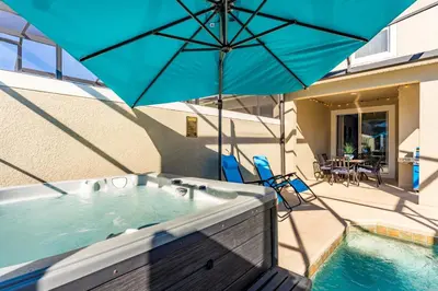 a hot tub with an umbrella on a patio at Family Retreat near Disney with Pool & Hot Tub! in Kissimmee