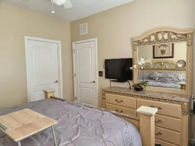 a bedroom with a bed and a dresser with a mirror at Comfortable Apartment, Close to Disney World in Kissimmee