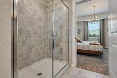 a bathroom with a walk in shower and a bedroom at Modern Luxe Condo - Stunning Design in Kissimmee