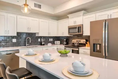 a kitchen with white cabinets and a stainless steel refrigerator at Urban Elegance - Modern Retreat in Kissimmee