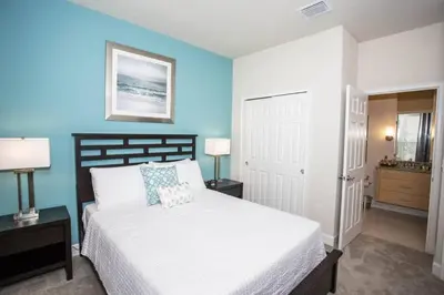 a bedroom with a white bed and a blue wall at Charming Cozy Haven in Orlando