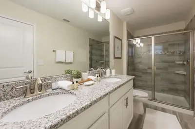 a white bathroom with two sinks and a shower at Chic Luxury Haven - Unforgettable Retreat in Kissimmee