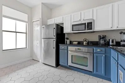 a kitchen with blue cabinets and a refrigerator at 4 BR Hot Tub Cozy Decor @ Regal Oaks RO2761N in Kissimmee