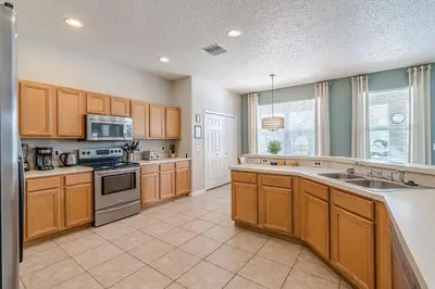 a large kitchen with wooden cabinets and a sink at 8575 - 7th Heaven Villa in Kissimmee