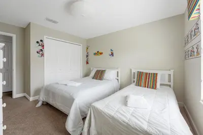two beds in a bedroom with white walls at Storey Lake Townhome 3076 in Kissimmee