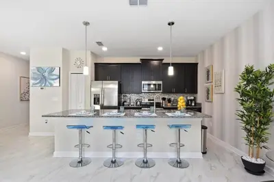 a kitchen with a large island with blue bar stools at Storey Lake Townhome 3076 in Kissimmee
