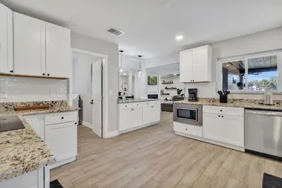 a large kitchen with white cabinets and wooden floors at Modern Lake Front Casita near Winter Park! in Orlando