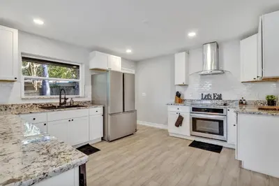 a kitchen with white cabinets and stainless steel appliances at Modern Lake Front Casita near Winter Park! in Orlando