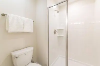 a white bathroom with a shower and a toilet at Best Vacation Villa, Themed Beds, Private Pool in Kissimmee