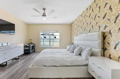 a bedroom with a white bed and a wall at 5BR Themed Pool Home Near Disney World in Kissimmee