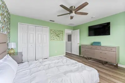 a bedroom with green walls and a bed with a ceiling fan at 5BR Themed Pool Home Near Disney World in Kissimmee