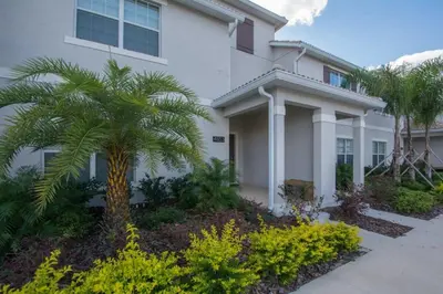 a white house with a palm tree in front of it at Prime Locale - Vacation Paradise in Kissimmee
