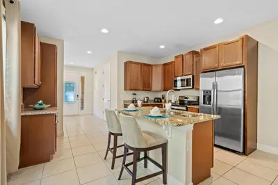 a kitchen with wooden cabinets and a island with bar stools at 8 Bd home with Themed rooms and Pool 2308 in Orlando
