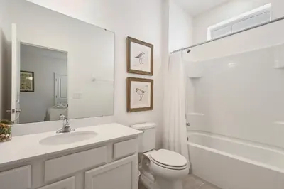 a white bathroom with a toilet and a sink at Spacious Family Reunion 15BR Home Pool Spa Game Rm in Kissimmee