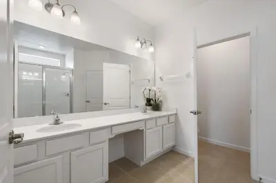 a white bathroom with a sink and a mirror at Spacious Family Reunion 15BR Home Pool Spa Game Rm in Kissimmee