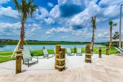 a patio with chairs and palm trees next to a lake at Disney World-House Up to 18 ppl at Storey Lake-Cloud9 in Kissimmee
