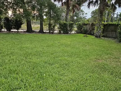 a yard with green grass and trees and a fence at The Farm House in Sanford