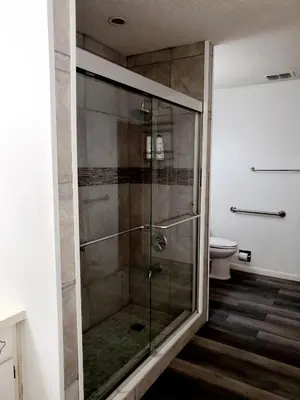 a glass shower in a bathroom with a toilet at The Farm House in Sanford