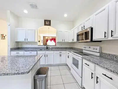 a kitchen with white cabinets and granite counter tops at Golden Beach Villa home in Kissimmee