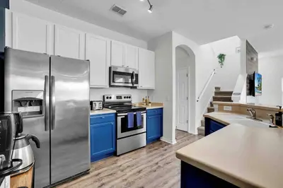 a kitchen with a stainless steel refrigerator and blue cabinets at Remarkable Cozy 4Bed-3Ba Townhouse in Kissimmee