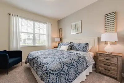a bedroom with a bed and a chair and a window at Luxury 5BR Home, Private Pool, Prime Location in Kissimmee