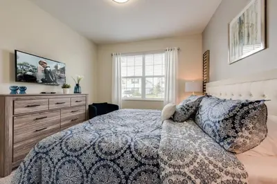 a bedroom with a bed with a tv and a dresser at Luxury 5BR Home, Private Pool, Prime Location in Kissimmee