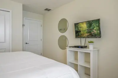 a white bedroom with a bed and two mirrors at Cozy Home Near Disney Parks - Prime Location in Kissimmee