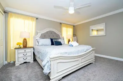 a bedroom with a white bed and a ceiling fan at Vibrant Themed Home Prime Location in Kissimmee