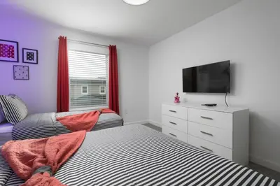 a bedroom with two beds and a flat screen tv at Modern Chic-Spacious, Private Pool, Prime Location in Kissimmee