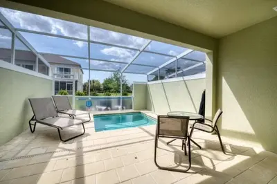a patio with a pool and two chairs and a table at Spacious Comfortable Perfect Vacation in Orlando