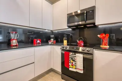 a kitchen with white cabinets and a black stove top oven at Modern Luxury Retreat - Mickey & Harry Potter Beds in Orlando