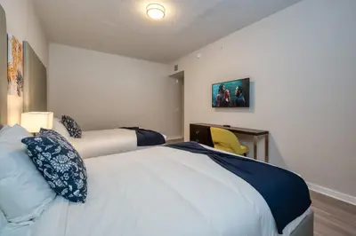a bedroom with two beds and a desk with a chair at Prime Location-Spacious Condo for 8 Guests in Orlando