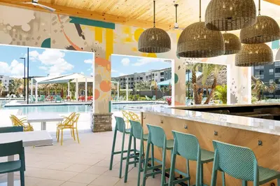 a restaurant with a bar with chairs and a pool at Villatel Orlando Resort in Orlando