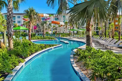 a pool at a resort with palm trees and chairs at Villatel Orlando Resort in Orlando