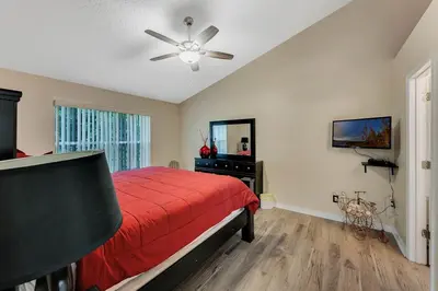 a bedroom with a red bed and a ceiling fan at Gorgeous Place Minutes Away from Attractions in Kissimmee